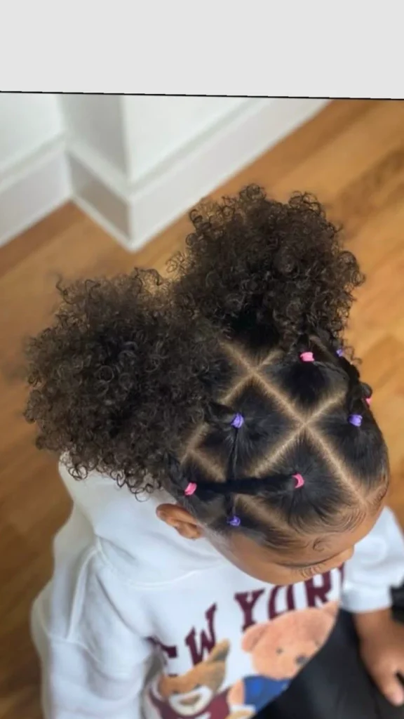 Toddler with curly hair styled in a diamond rubber band pattern leading to two high curly puffs