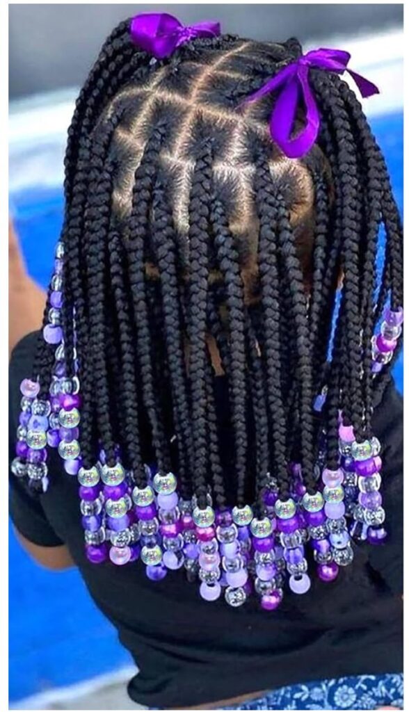 Young girl with beaded braids with half of it pulled up into a double ponytail