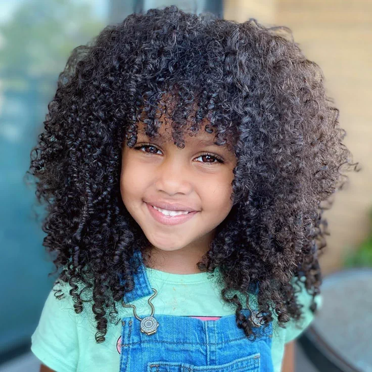 Smiling child with defined, springy 4A curls and curly bangs