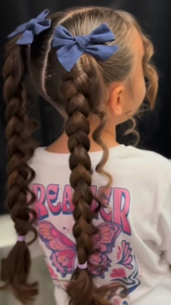 Young girl with hair styled in two low pigtails finished with bows