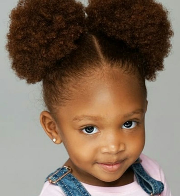 Young girl with 4C hair styled in two round double puffs with a center part