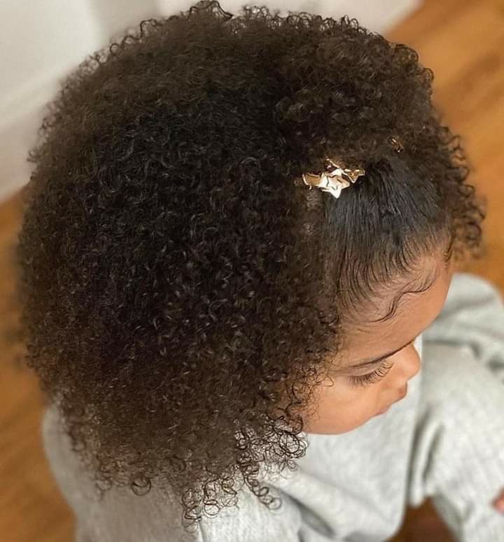 Young girl with curly hair styled in a half-up ponytail