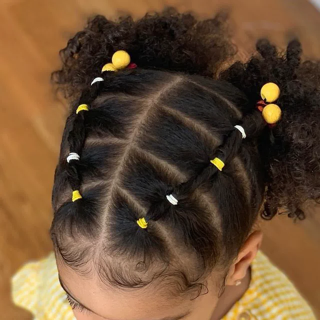 Young girl with curly hair styled in a half-up ponytail with a bow