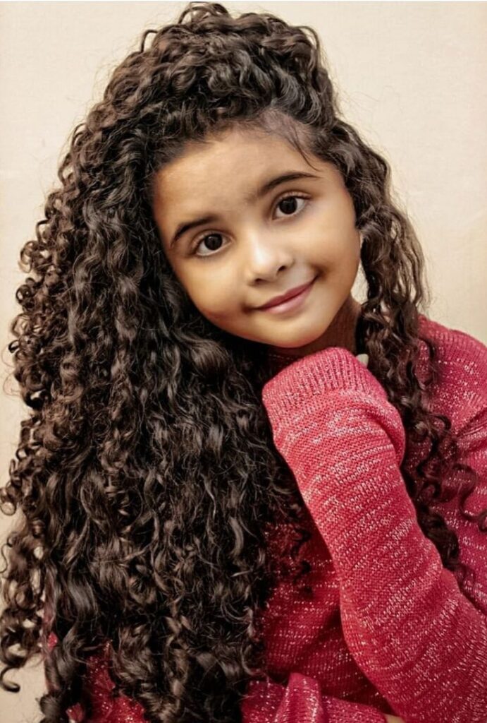 Young girl with medium-length 3B curls forming tight, springy ringlets with lots of volume.