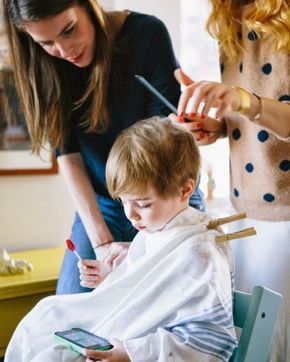 Little boy getting a haircut at home with mom