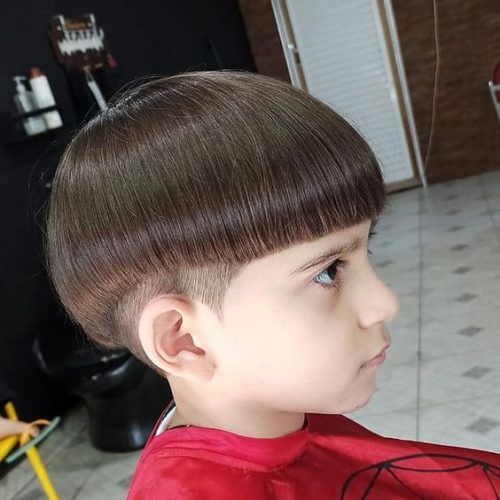 Side profile close-up of a young boy with a mushroom cut haircut, a smooth, rounded shape on top with a tapered undercut on the sides.