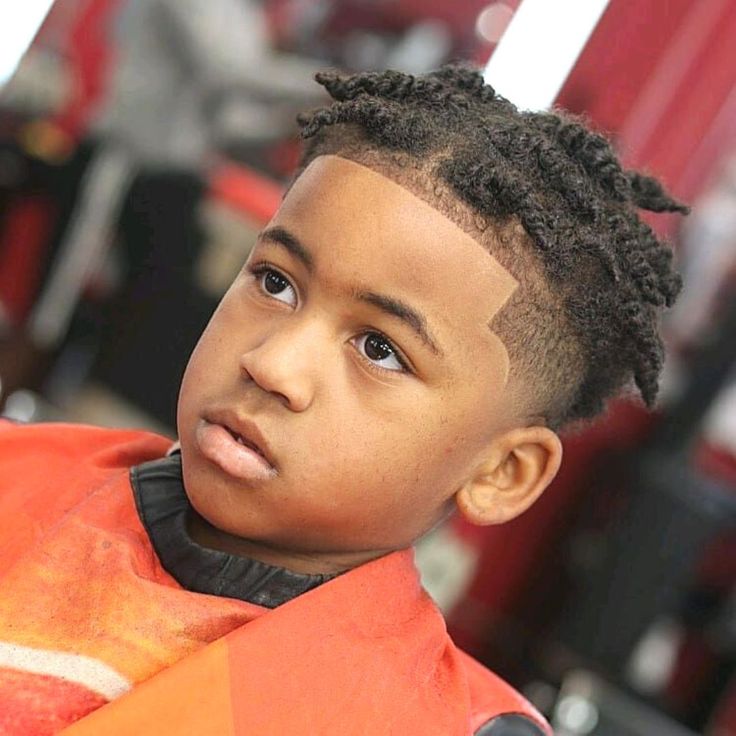 Close-up of a young boy with short twists, shorter twisted coils on top blending into a fade on the sides.