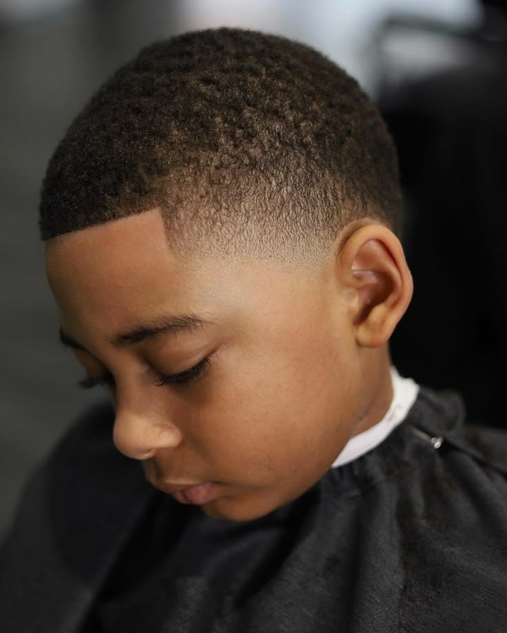 Side profile close-up of a young boy with a shadow fade haircut, short textured hair on top blending softly and gradually into the sides.