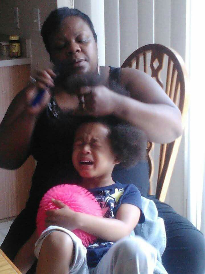 A little girl crying out of discomfort while getting her hair detangled 