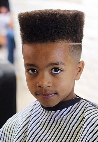 Close-up of a young boy with a flat top haircut, a level, squared-off shape on top blending into a fade on the sides.