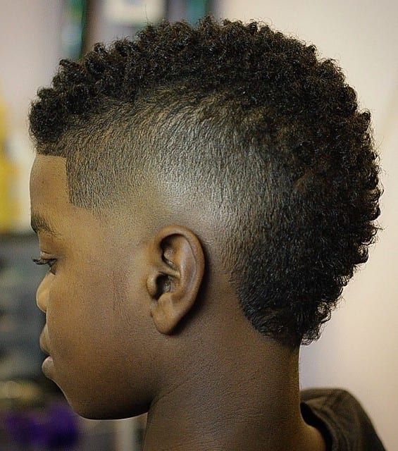 Side profile close-up of a young boy with a Frohawk haircut, coily hair kept fuller through the crown with faded sides.
