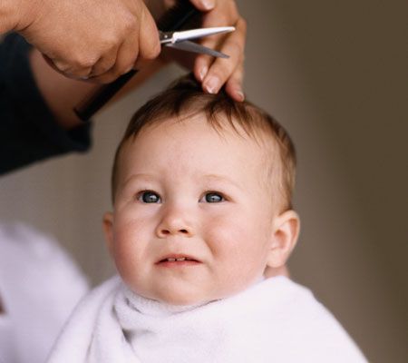 A hand trimming a babys hair