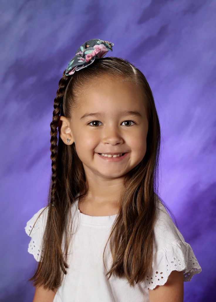 Smiling child in a school picture day portrait with a braided side accent and floral hair clip