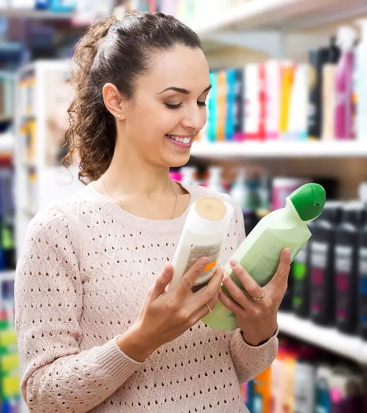 "Woman smiling while comparing labels on two hair product bottles in a store aisle
