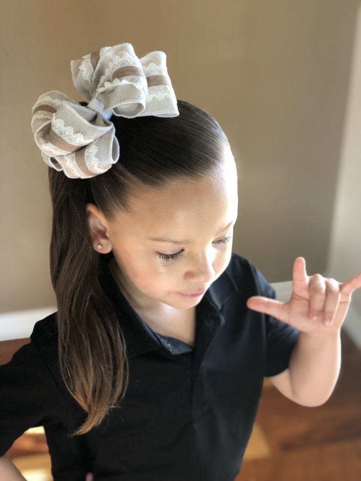 Child wearing a side ponytail gathered to one side with a bow at the base