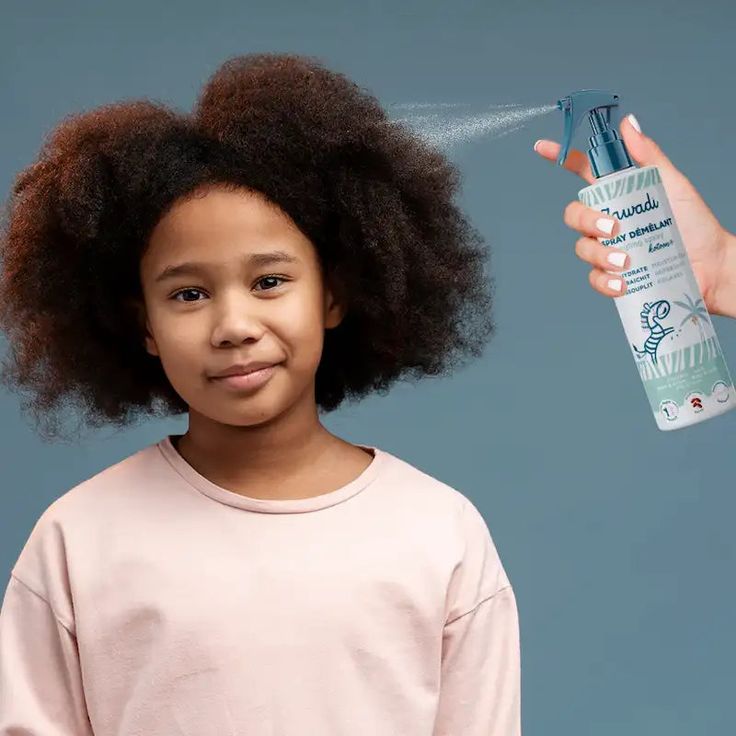 child getting detangling spray applied to afro