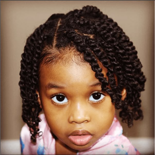 A close-up of a toddler with neat, shoulder-length two-strand twists parted down the middle."