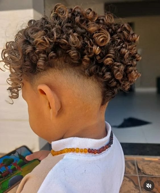 Side and back view of a young boy with a curly undercut haircut, tightly shaved sides paired with long, defined curls left on top.