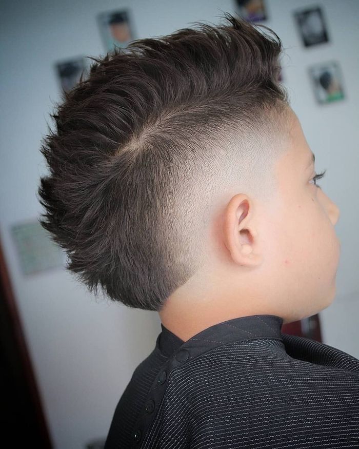 Side and back view of a young boy with a mohawk fade haircut, sides tapered down to skin with a spiked strip of longer hair styled upright down the center.