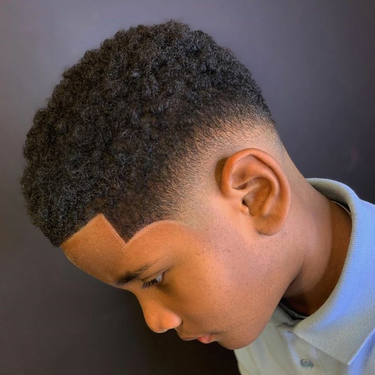 Side profile close-up of a young boy with an afro fade haircut, a skin fade on the sides paired with a full, coily afro on top.