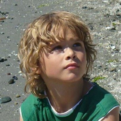 Close-up of a young boy at the beach with a shag haircut, layered, tousled hair with natural movement throughout.