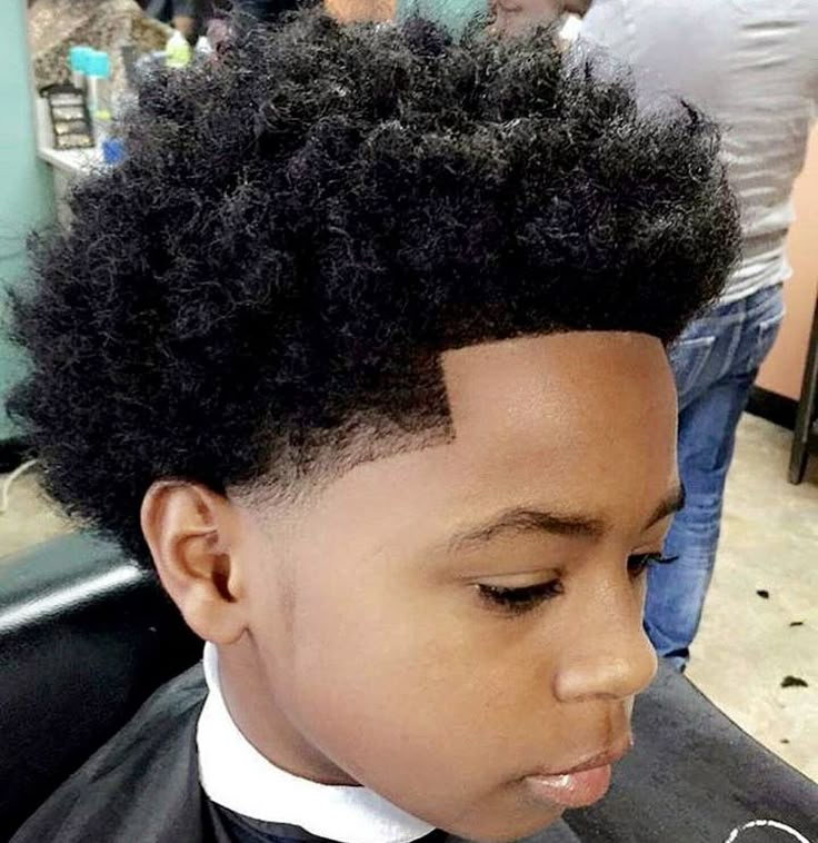 Side profile close-up of a young boy with a tapered afro haircut, coily hair full and rounded on top blending into tapered sides.