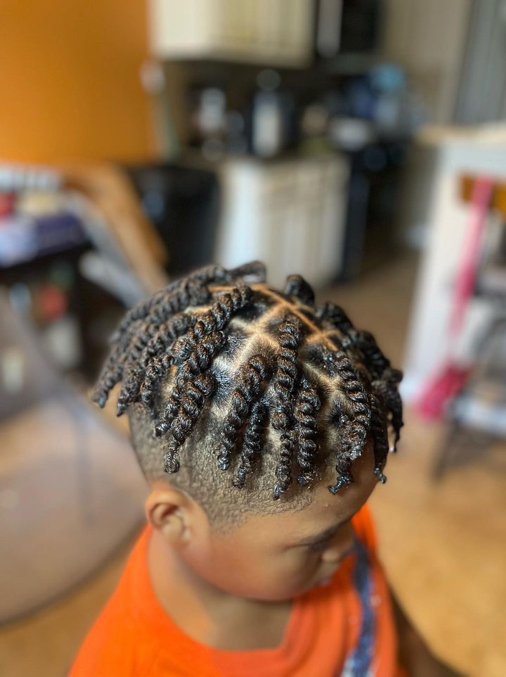 Top-down close-up of a young boy with a twist fade haircut, twisted sections radiating from the crown blending into a fade on the sides.