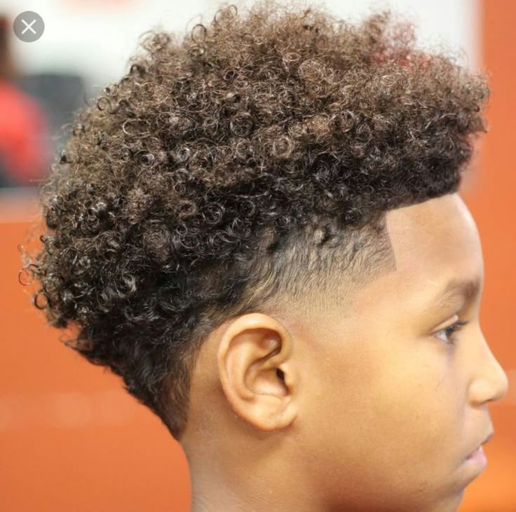 Side profile close-up of a young boy with a taper fade haircut, curly hair left loose on top, blending into a smooth fade on the sides.
