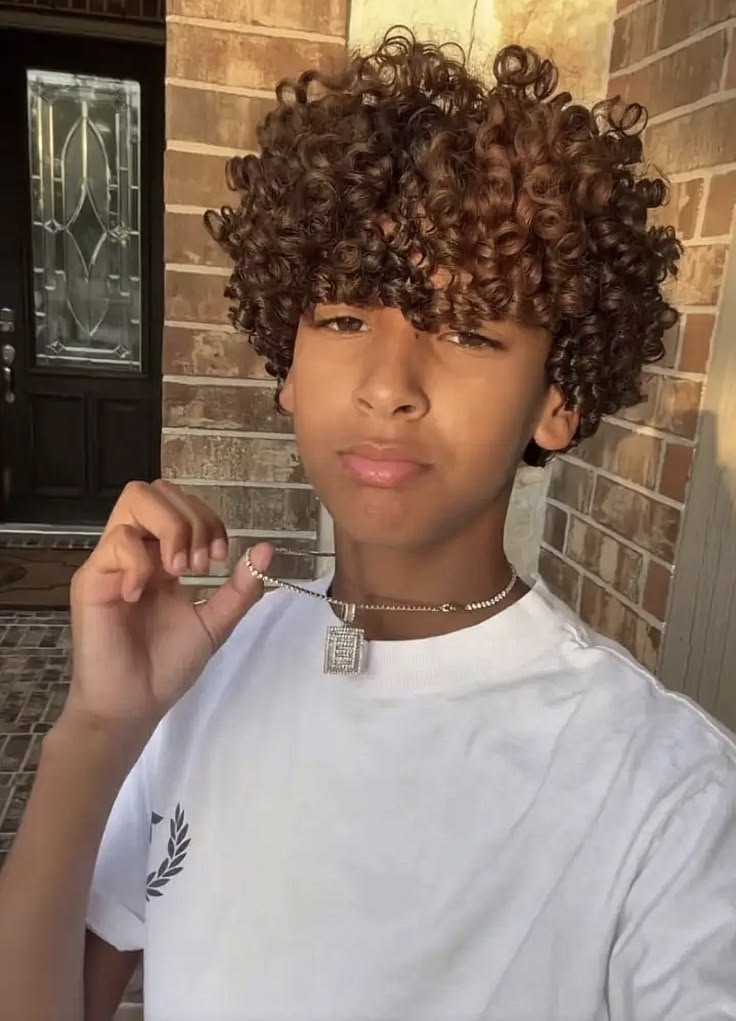 Close-up of a boy with loose, layered curly hair and a soft curly fringe falling over the forehead.