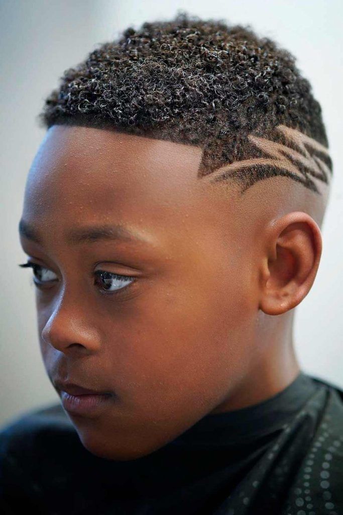Close-up of a boy with short curly hair on top and a zigzag line design shaved into the fade.