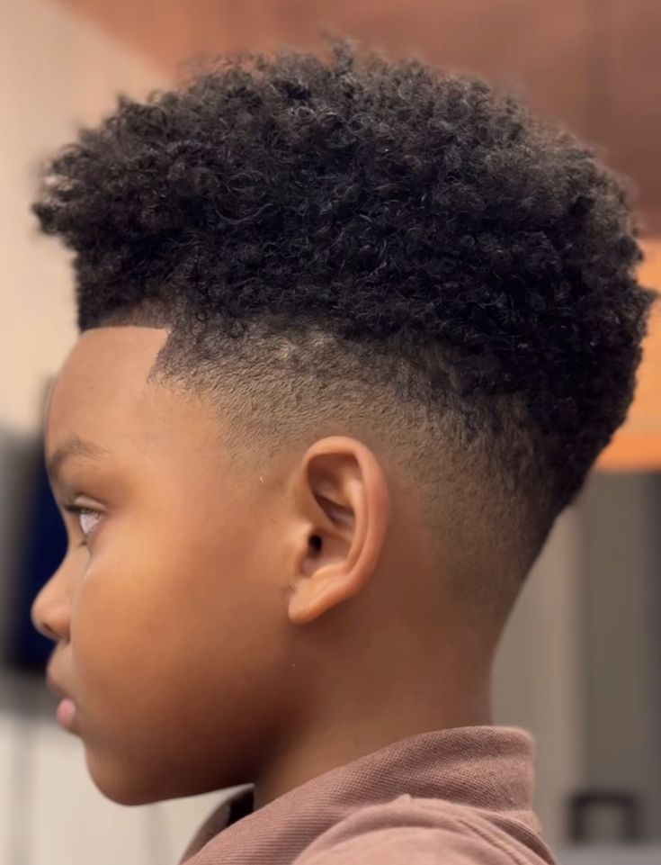 A boy with a tapered afro, shorter sides and a rounded, fuller top.