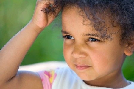 A young child scratching her hair because of dry scalp