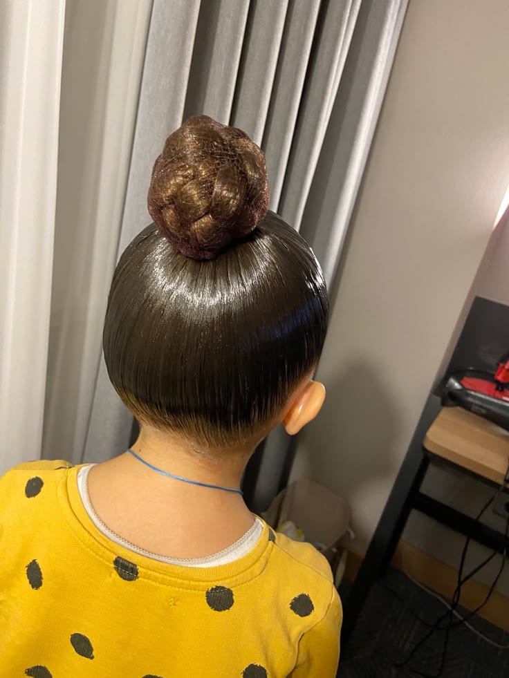 Child with hair twisted into a neat top knot bun at the crown