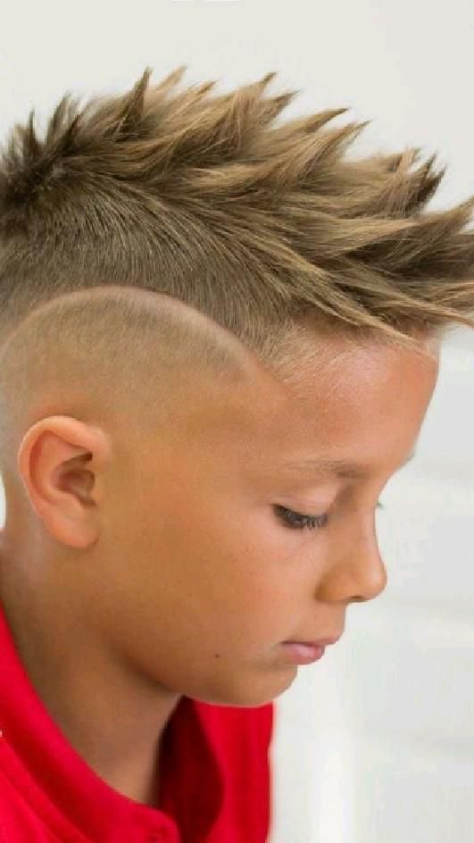 Side profile close-up of a young boy with a faux hawk haircut, hair styled upright and spiky down the center with short, tapered sides.