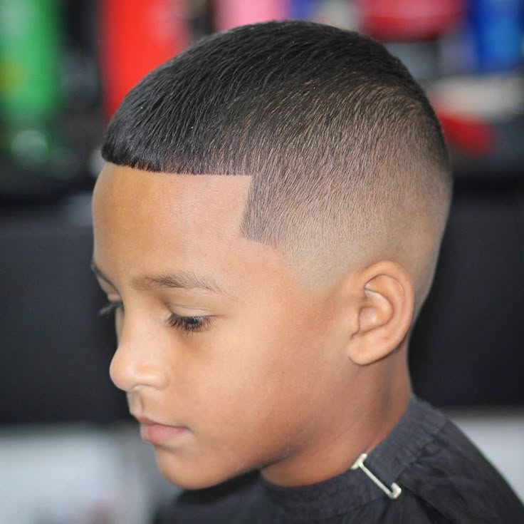 Side profile close-up of a young boy with a regulation cut haircut, short tapered length with a sharp, defined hairline edge and faded sides.