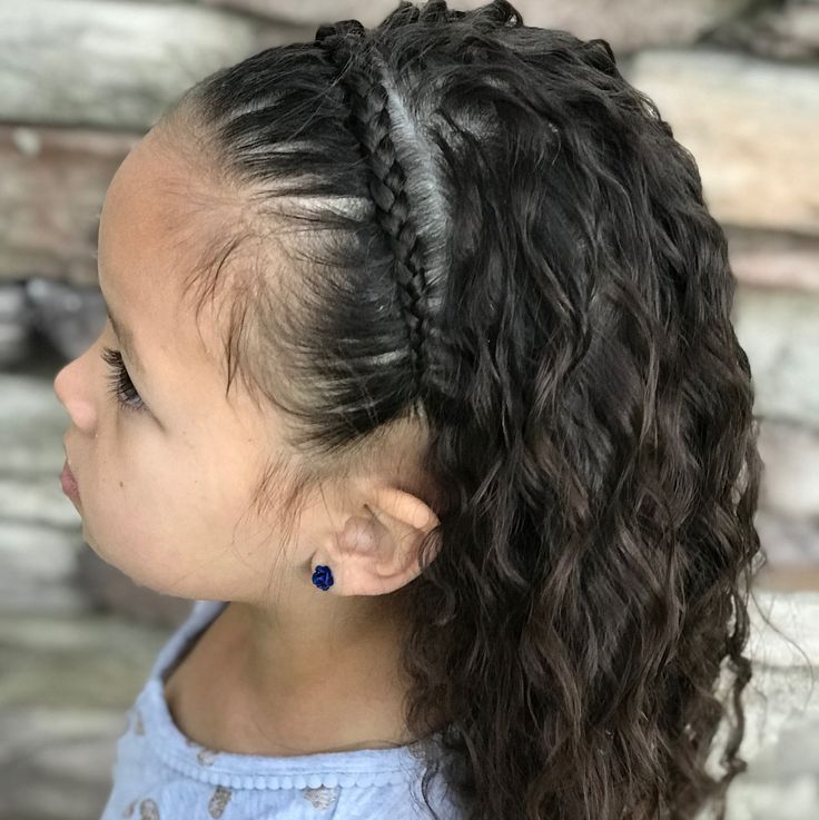Young girl with curly hair styled with a thin braided headband, loose curls flowing down