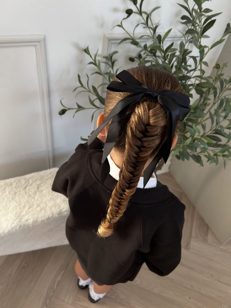 Young girl with a fishtail braid tied off with a black ribbon at the top