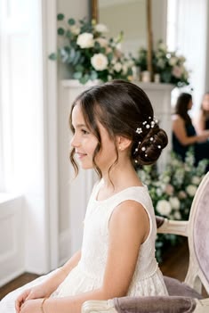 Young girl with a low chignon updo accented with pearl pins, smiling in profile