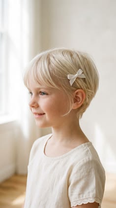 Young girl with a pixie cut wearing a small white satin bow above her ear, dressed for a formal graduation event