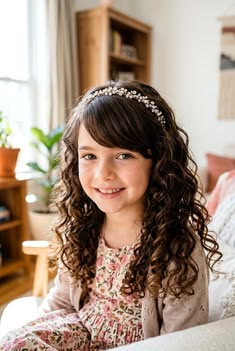 Young girl with defined curly hair wearing a sparkly rhinestone headband, smiling