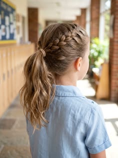 Young girl with a French braid leading into a low ponytail, loose wavy ends visible