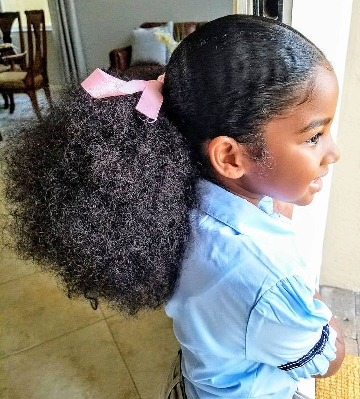 Girl with a low afro puff hairstyle and a pink bow