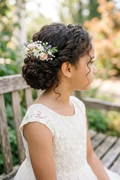 Girl with soft low curly bun updo and floral hair accessory