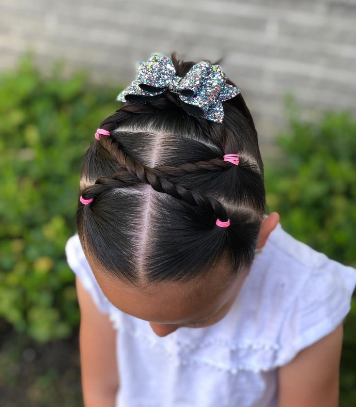 Overhead view of a girl with crisscross rope twists leading into a ponytail with a glitter bow