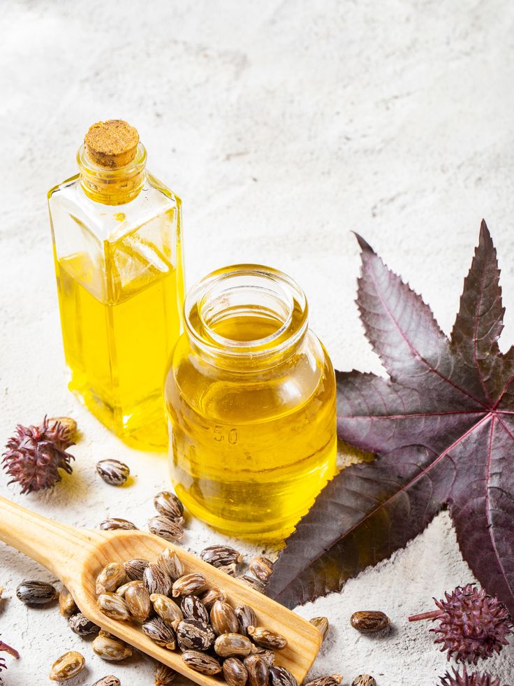 Two bottles of castor oil with castor seeds and leaves
