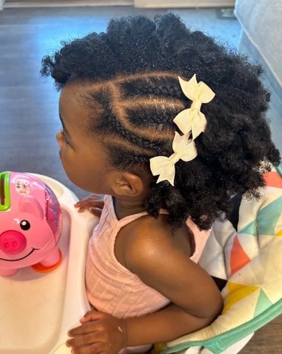 Child with side braided sections and natural curls, bow clips