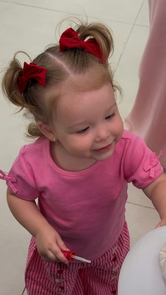 Toddler with two high pigtails tied with red bows