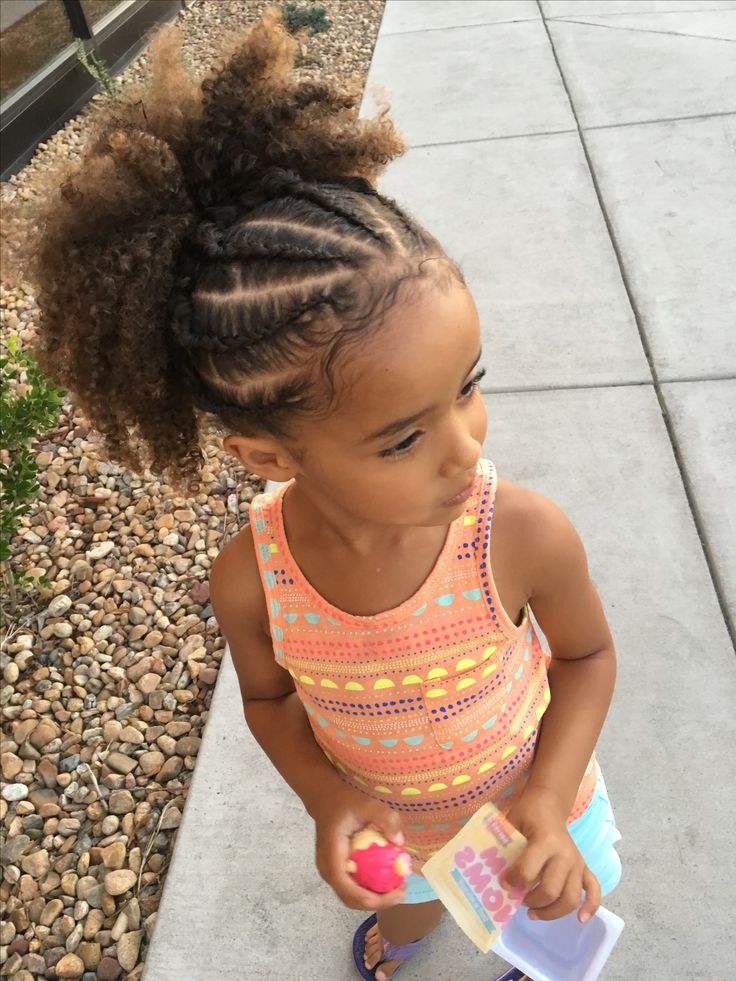 Child with coily curly hair and braided sections, standing outdoors