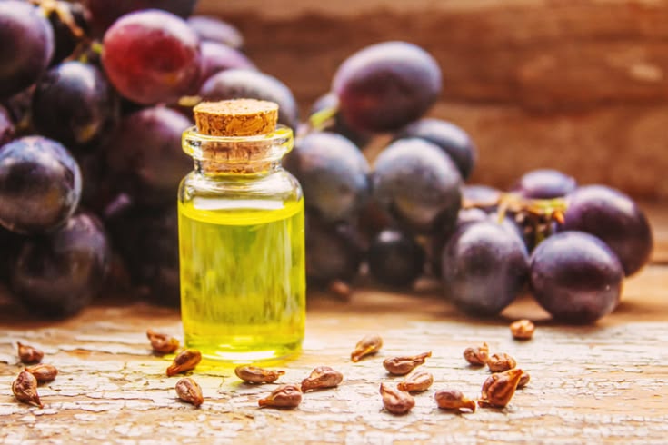 Bottle of grapeseed oil with grapes and seeds