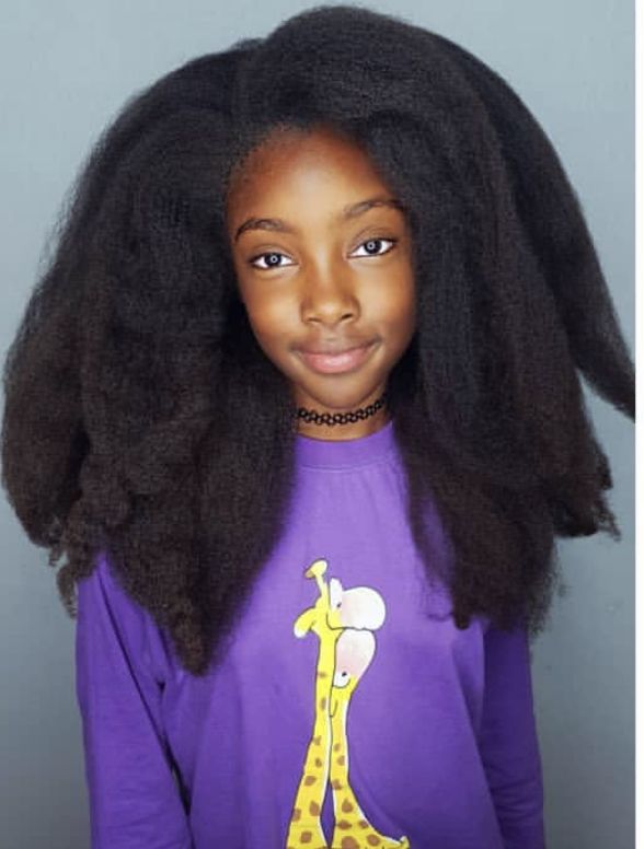 Smiling child with long, voluminous natural hair.